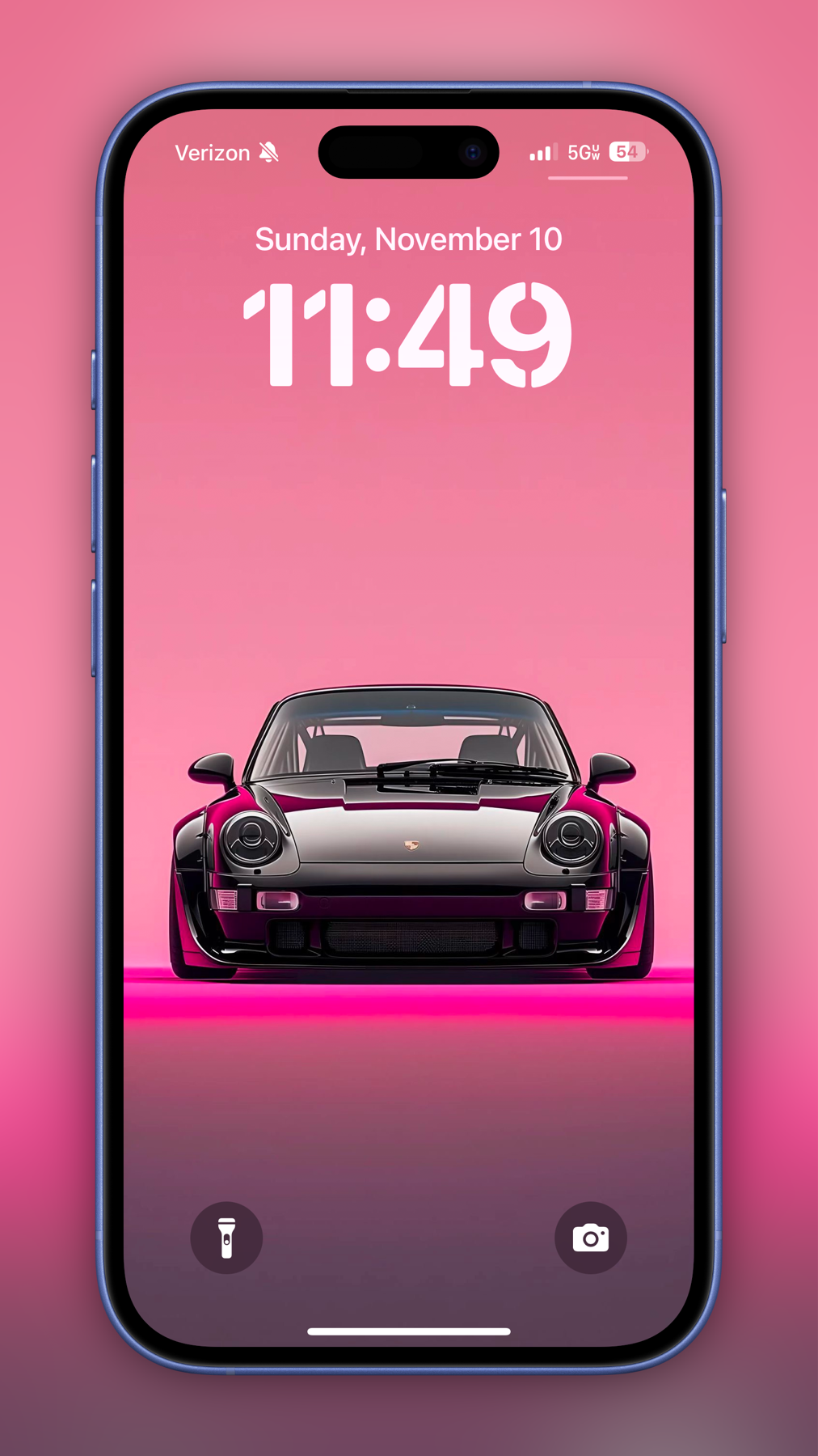 A smartphone lock screen displaying the time “11:49” on Sunday, November 10. The wallpaper features a sleek black sports car on a pink gradient background. The phone shows a Verizon signal, 5G connection.